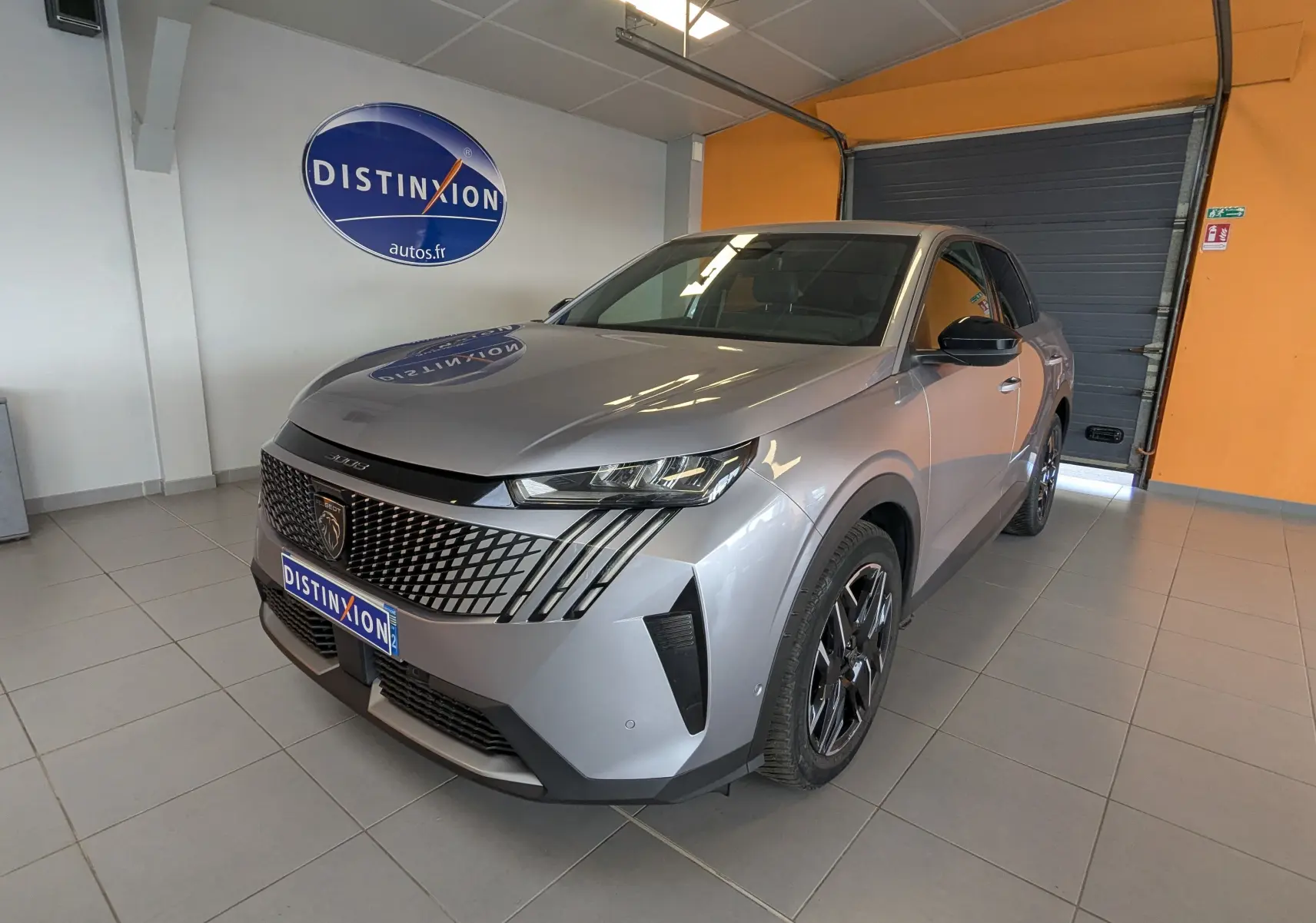 Peugeot 3008 gris vue 3/4 avant droit en intérieur, avec calandre distinctive et jantes noires brillantes.