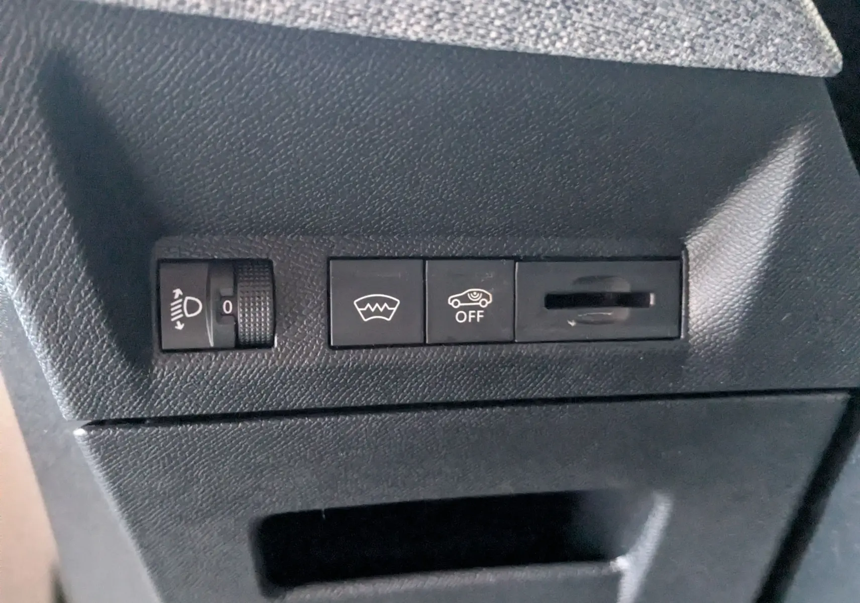 Détail intérieur montrant les commandes de réglage des phares, dégivrage et désactivation de l'assistance au maintien de voie sur Peugeot 3008 gris.