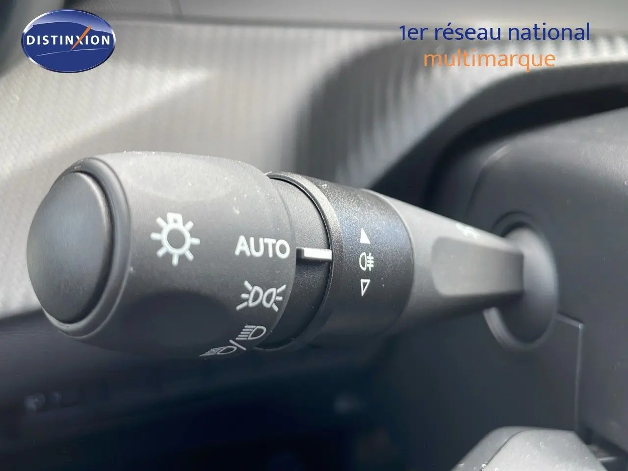 Gros plan sur la commande des feux automatiques à gauche du volant dans l'habitacle d'une Peugeot 2008 noire.