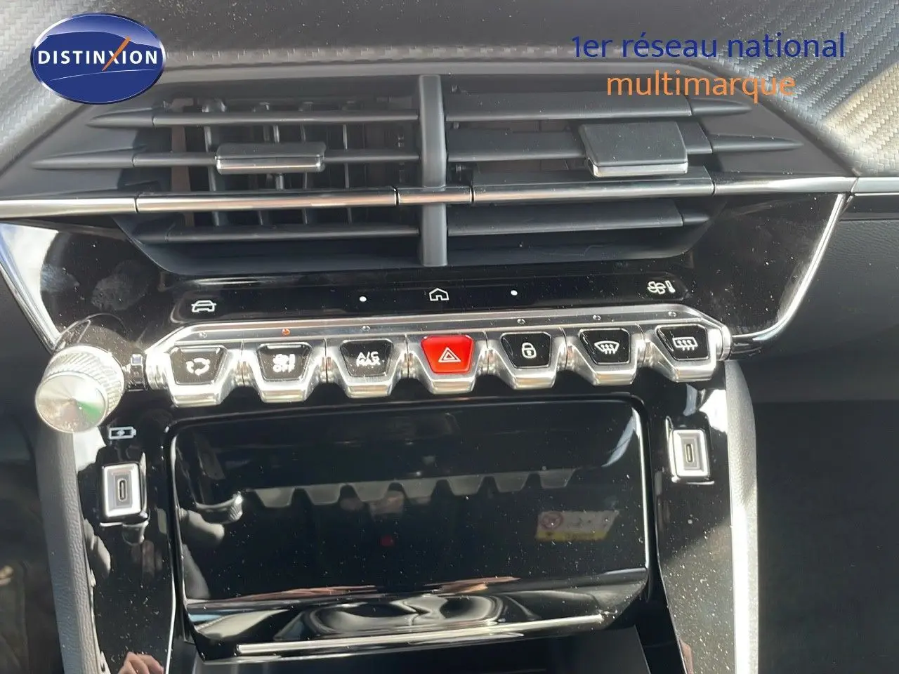 Gros plan sur la console centrale noire brillante du Peugeot 2008 2025, avec boutons de commande et aérateurs visibles.