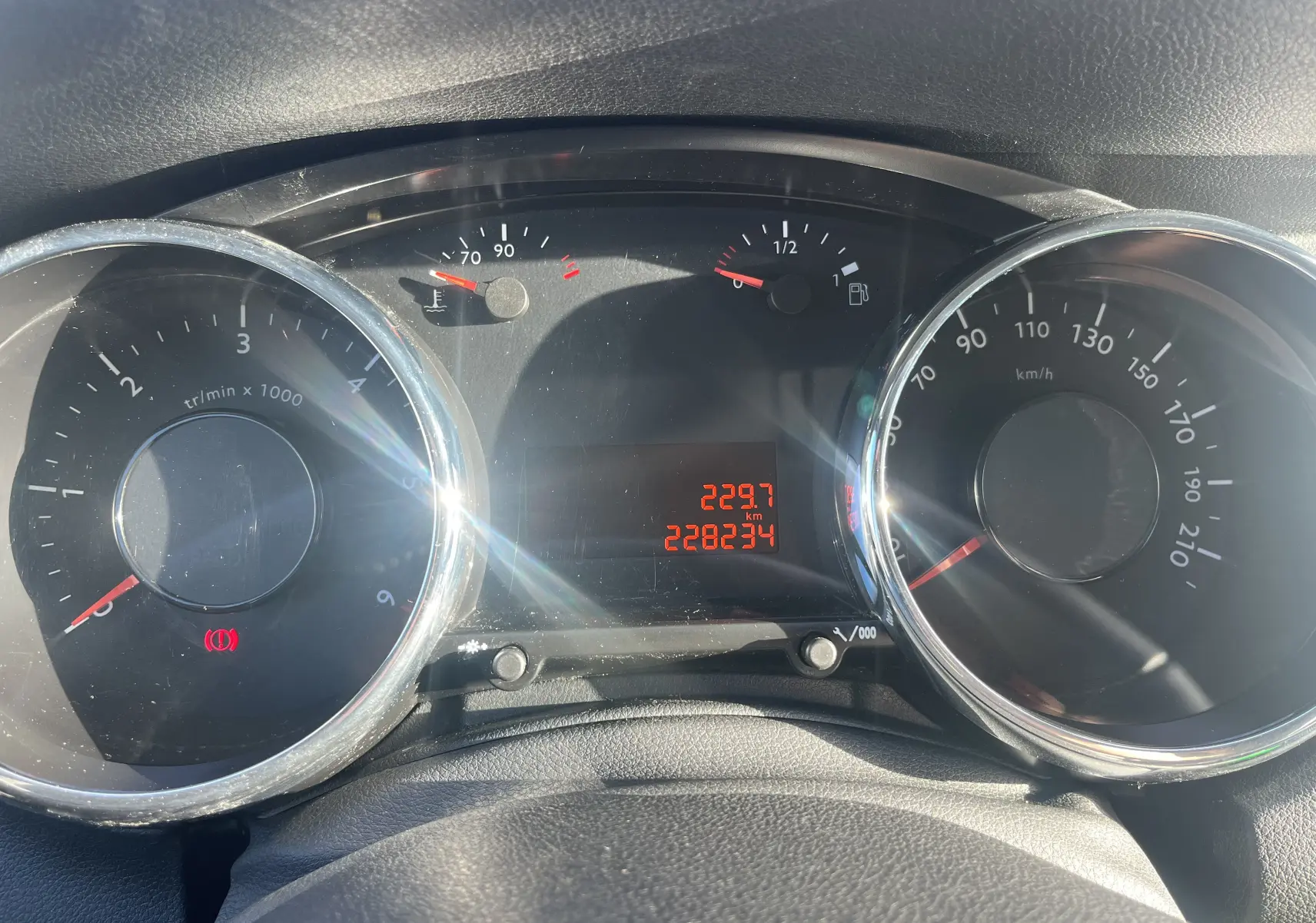 Vue rapprochée du tableau de bord du Peugeot 5008 2013, affichant compte-tours, vitesse et jauges avec rétroéclairage rouge.