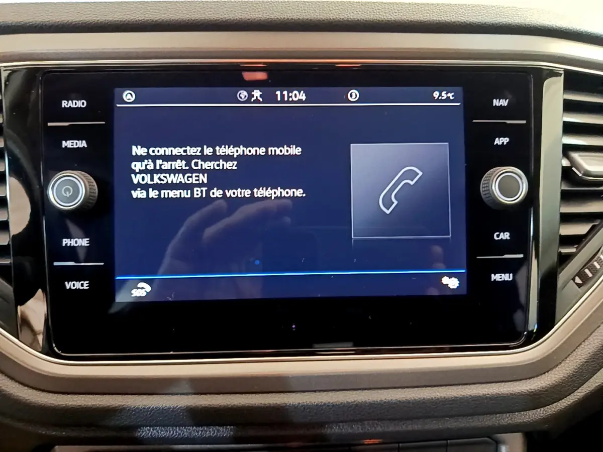 Écran tactile central du Volkswagen T-Roc 2021 affichant un message de connexion Bluetooth, entouré de boutons fonctionnels.