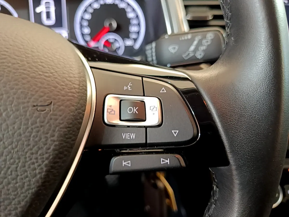 Gros plan sur les commandes multifonctions du volant cuir côté gauche du Volkswagen T-Roc gris foncé 2021.