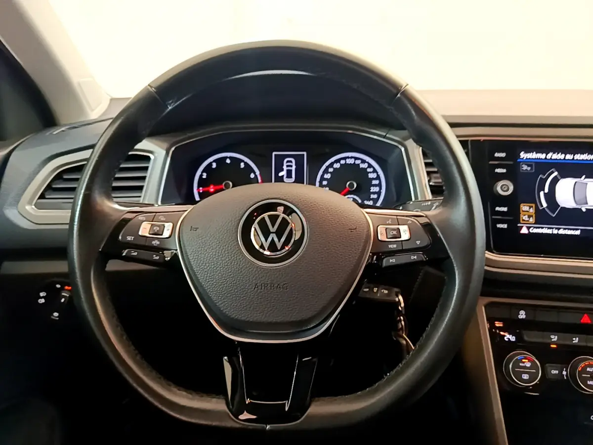 Vue rapprochée du volant cuir noir multifonctions du Volkswagen T-Roc 2021 avec tableau de bord numérique et écran tactile.