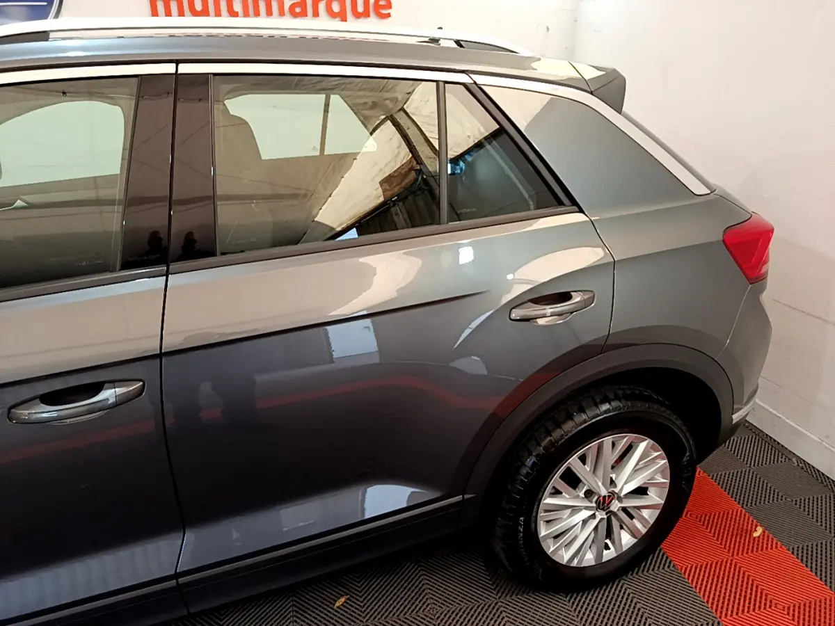 Vue latérale côté droit du Volkswagen T-Roc gris foncé, mettant en valeur la roue arrière et les vitres teintées.