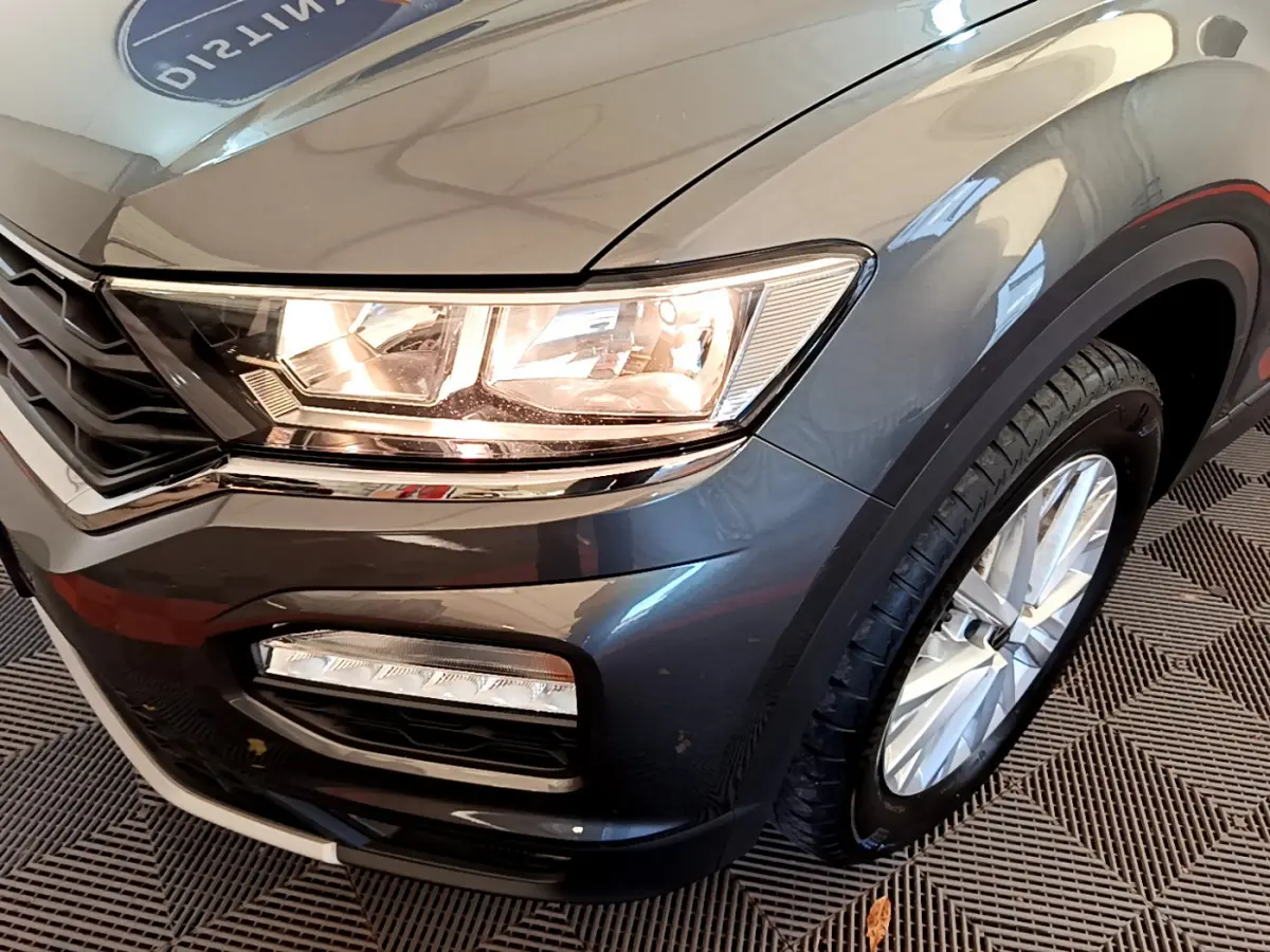 Gros plan sur l'avant droit gris foncé du Volkswagen T-Roc 1.0 TSI avec phares et feux antibrouillard visibles.