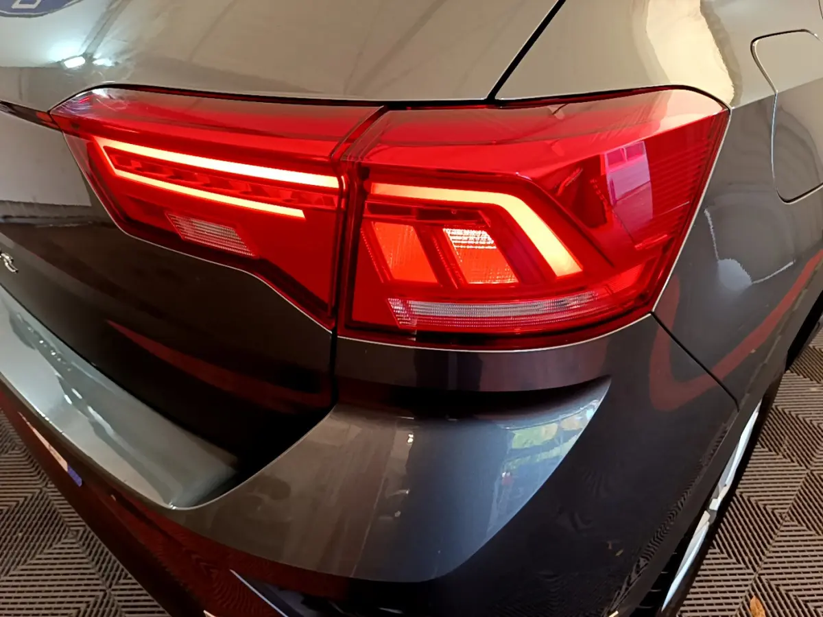 Gros plan sur le feu arrière droit rouge d’un Volkswagen T-Roc gris foncé 2021, finition Lounge Business.