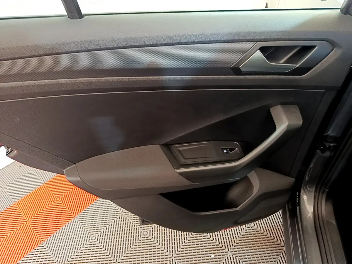 Porte intérieure côté droit gris foncé du Volkswagen T-Roc 1.0 TSI 110 Lounge Business avec poignée et commande de vitre.