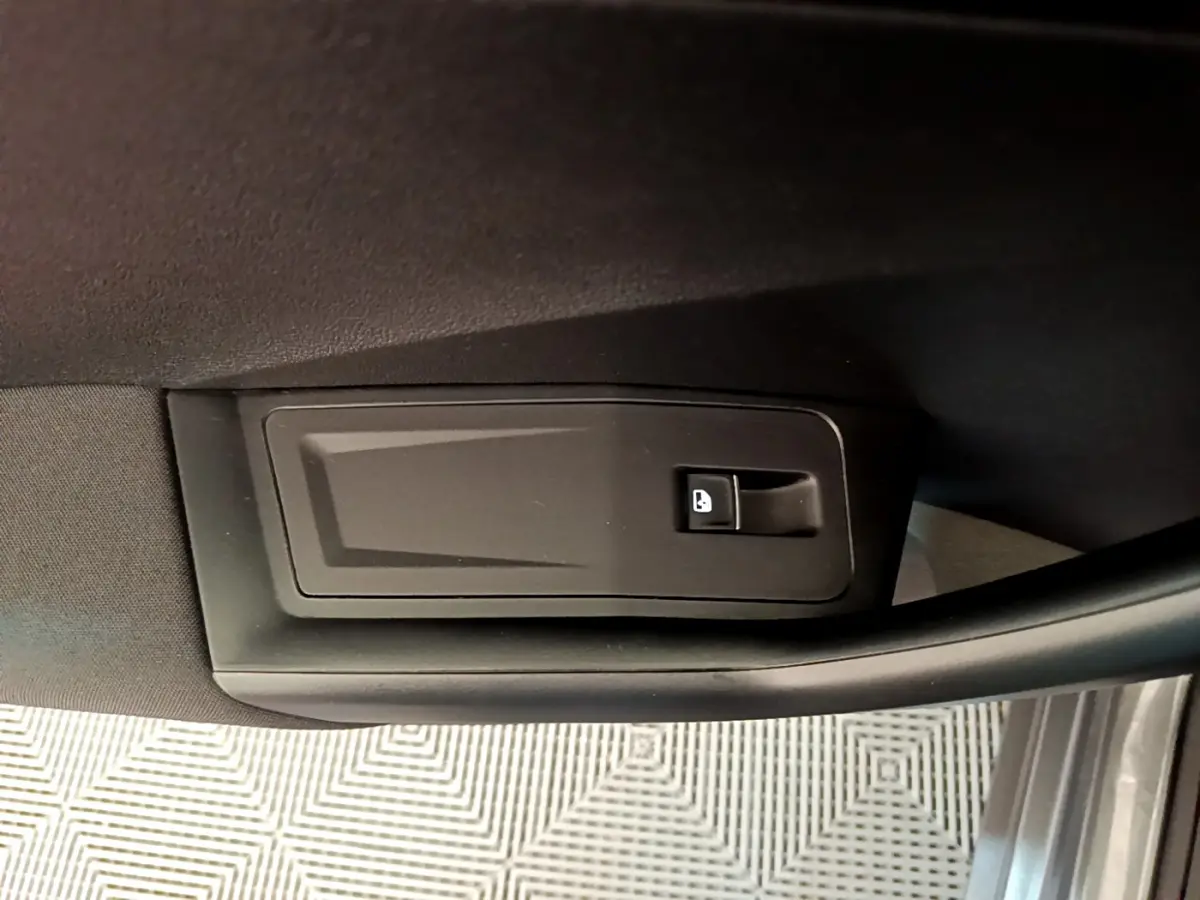 Bouton de verrouillage de porte sur panneau intérieur noir de la portière côté conducteur d'un Volkswagen T-Roc gris foncé.