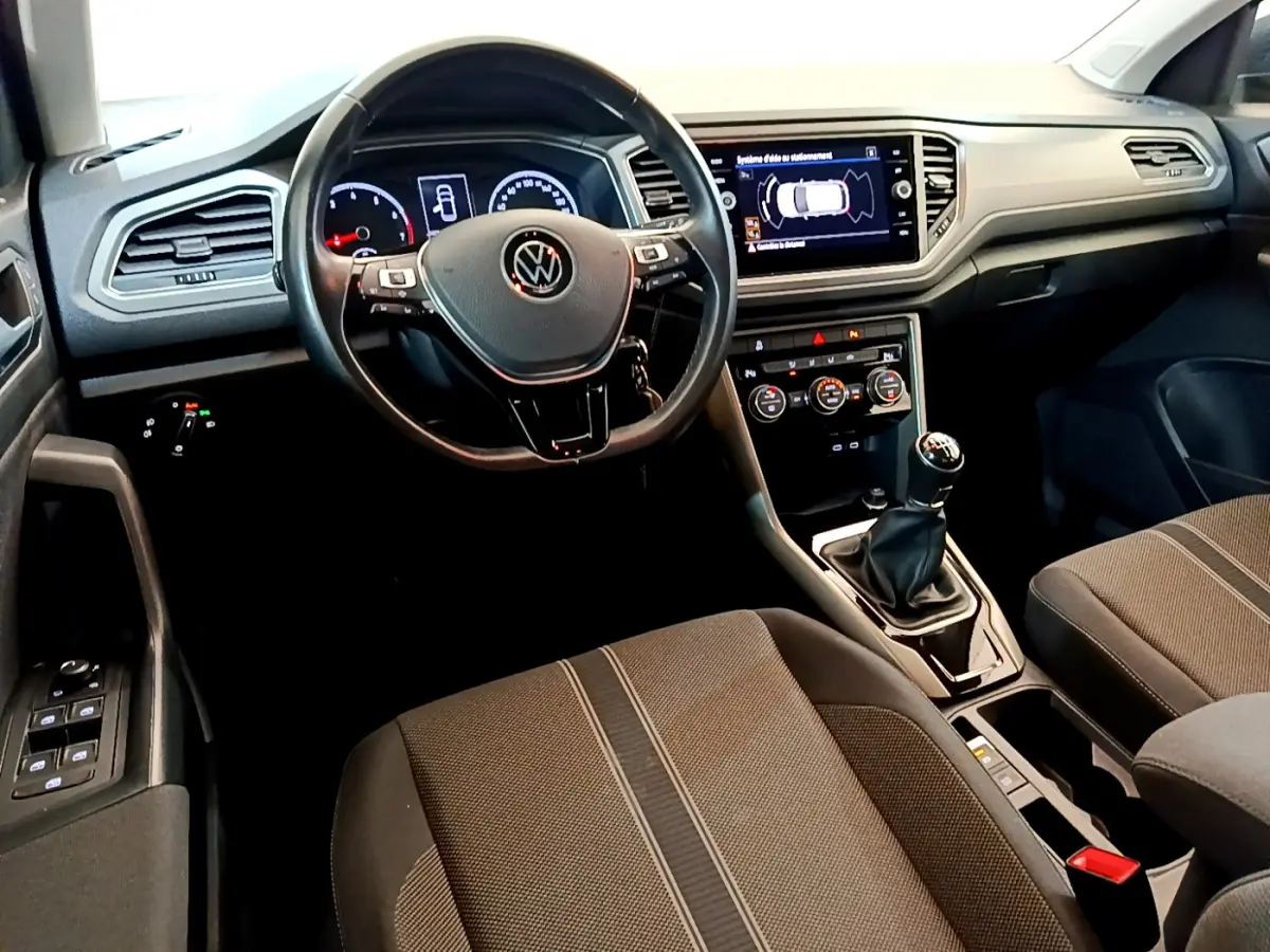 Intérieur du Volkswagen T-Roc 1.0 TSI 2021, vue depuis le siège conducteur, tableau de bord et console centrale avec écran tactile.