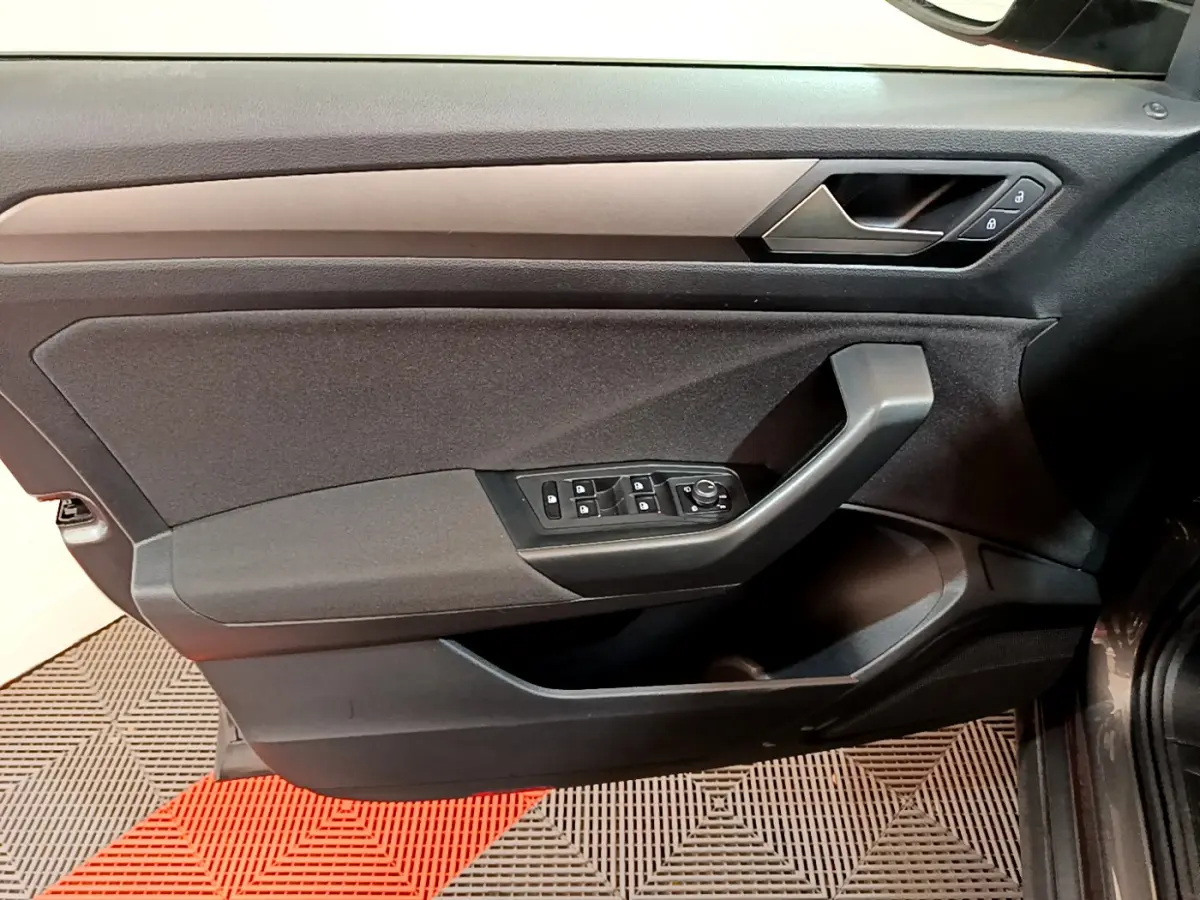 Vue intérieure du panneau de porte côté conducteur du Volkswagen T-Roc gris foncé, avec commandes électriques et poignée angulaire.