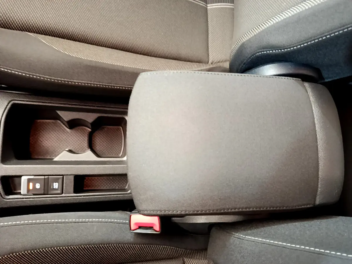 Gros plan sur l'accoudoir central et porte-gobelets du Volkswagen T-Roc gris foncé, intérieur tissu noir.