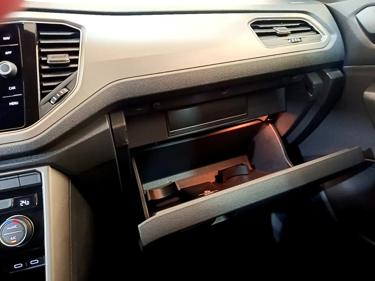 Intérieur du Volkswagen T-Roc 2021, vue du tableau de bord côté passager avec boîte à gants ouverte et éclairage intérieur.