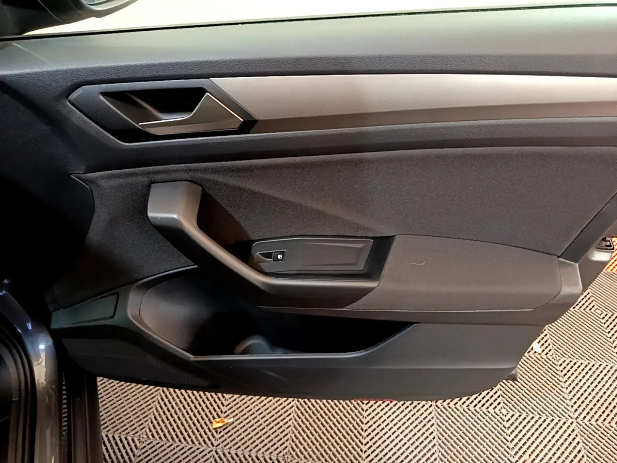 Vue rapprochée de la porte avant gauche gris foncé du Volkswagen T-Roc 2021 avec poignée et commande de vitre intégrée.