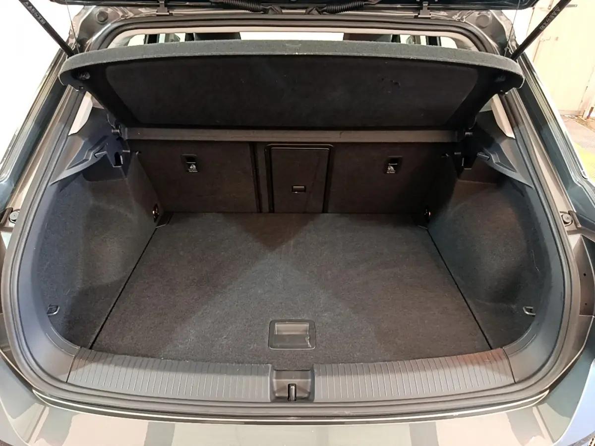 Coffre ouvert d'un Volkswagen T-Roc gris foncé, vue arrière montrant l'espace de chargement et la tablette amovible.