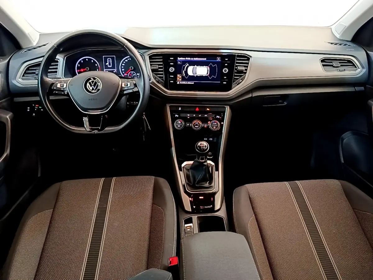 Vue intérieure avant du Volkswagen T-Roc 1.0 TSI 110 Lounge Business 2021, tableau de bord noir avec écran tactile central.
