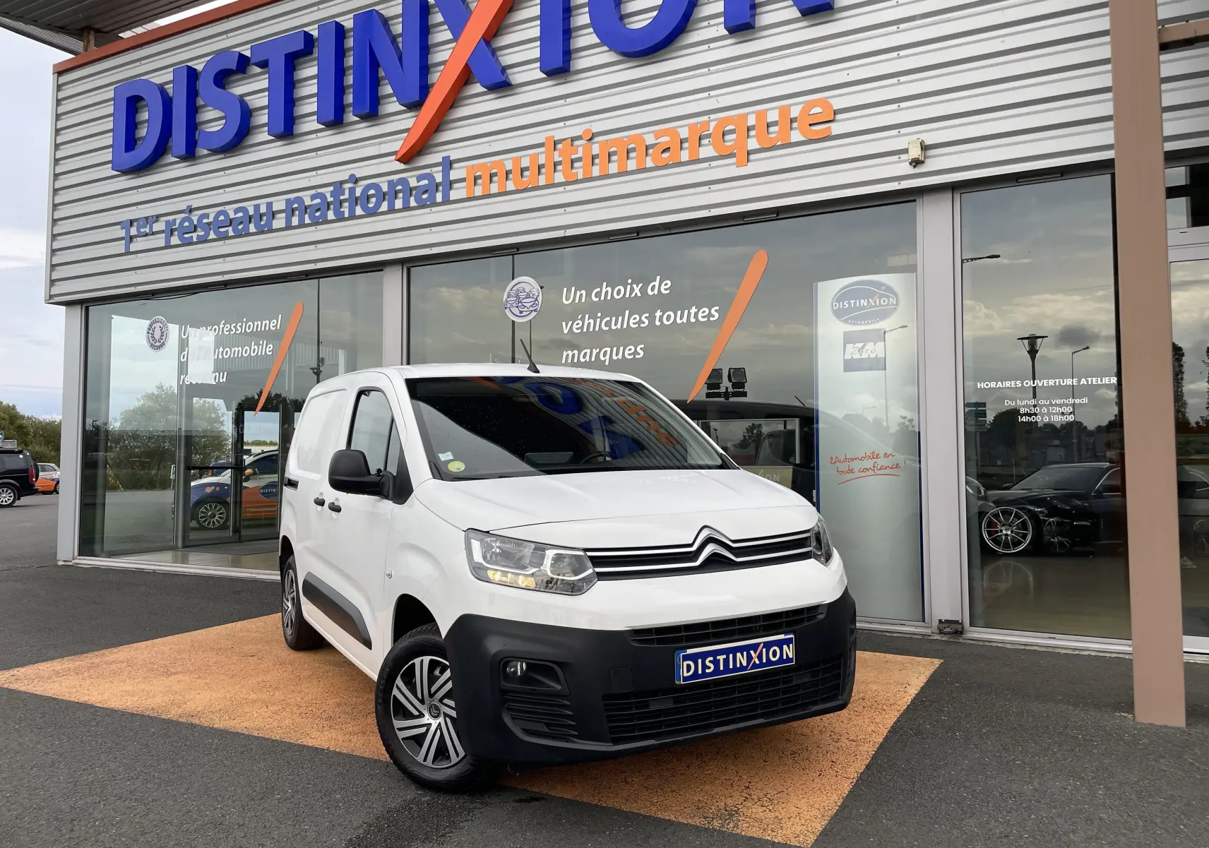 Citroën Berlingo blanc en 3/4 avant droit, avec pare-chocs noir et jantes alliage devant un concessionnaire Distinxion.