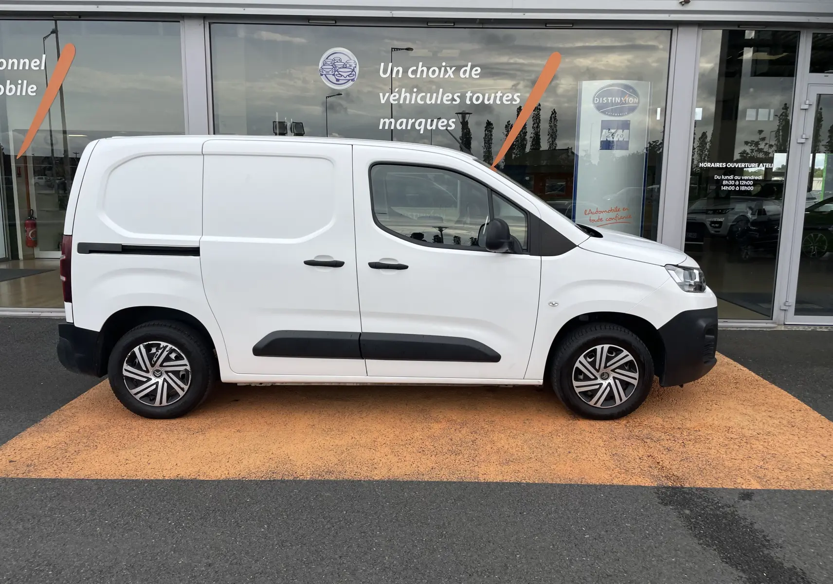 Profil droit d'un utilitaire blanc Citroën Berlingo 1.5 BlueHDi 2018 avec protections noires et jantes alliage.