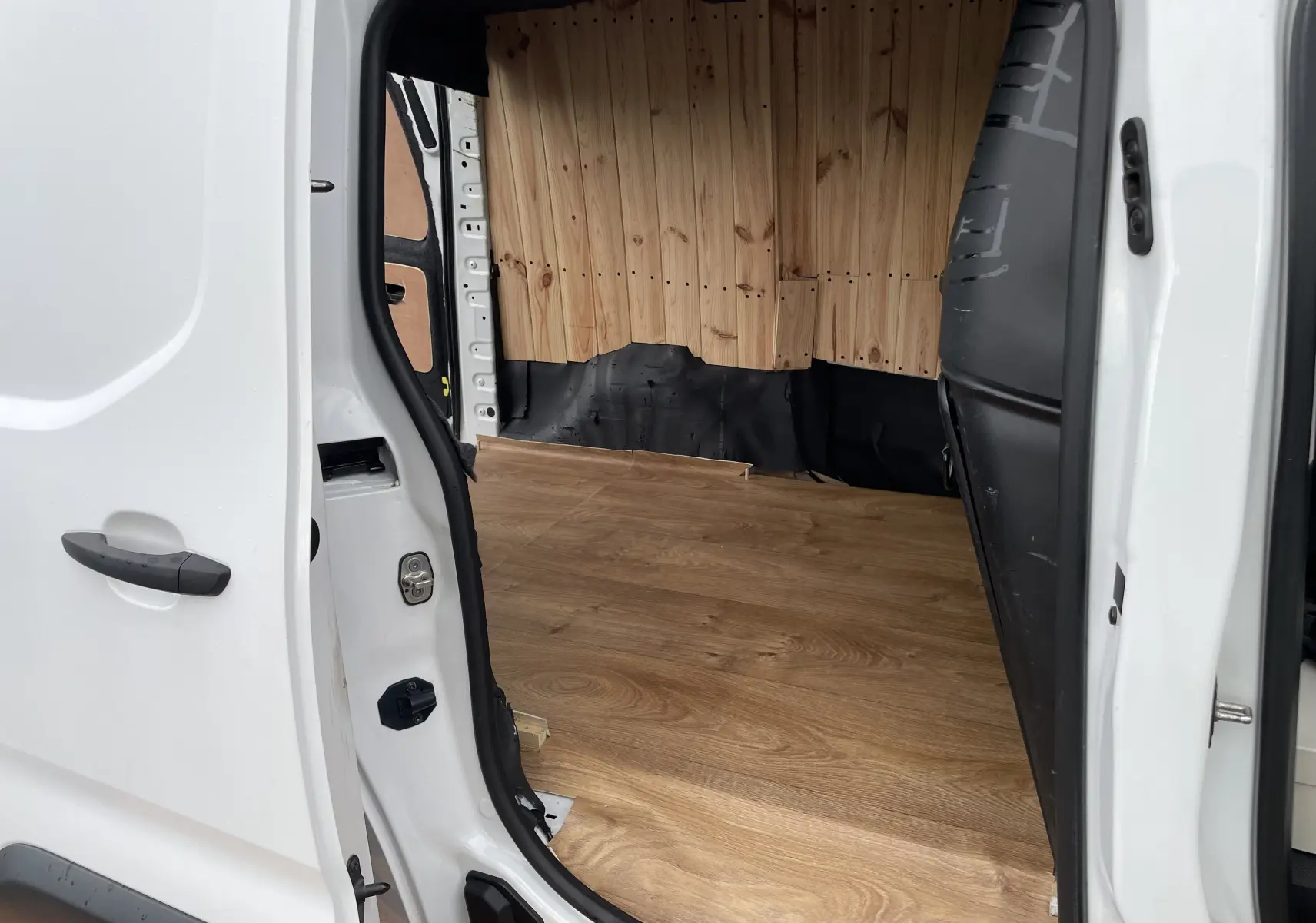 Vue intérieure côté droit du Citroën Berlingo blanc 2018, montrant l'aménagement bois du plancher et des parois.