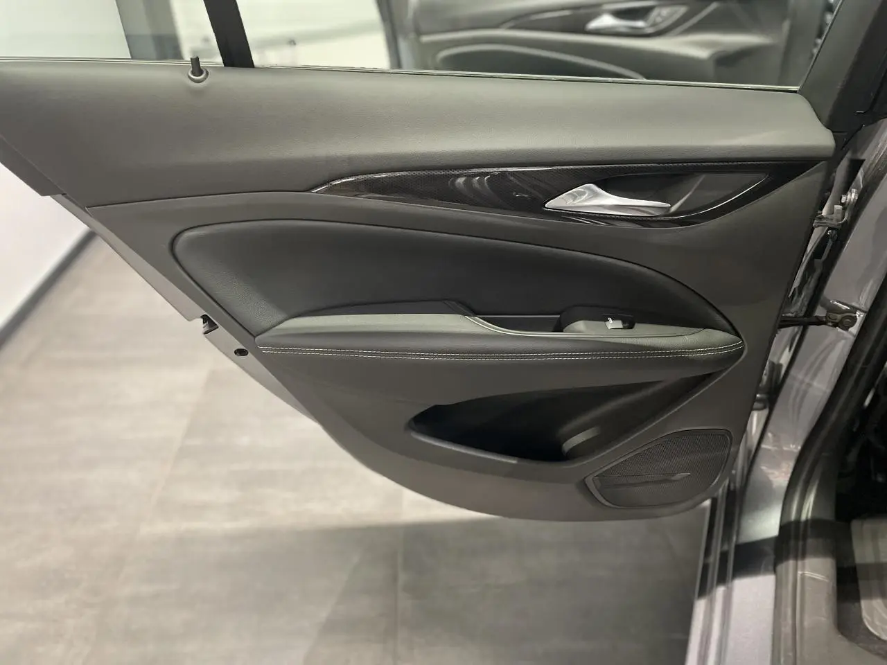 Gros plan sur la porte avant gauche gris clair de l'Opel Insignia Grand Sport avec garniture noire et insert décoratif.