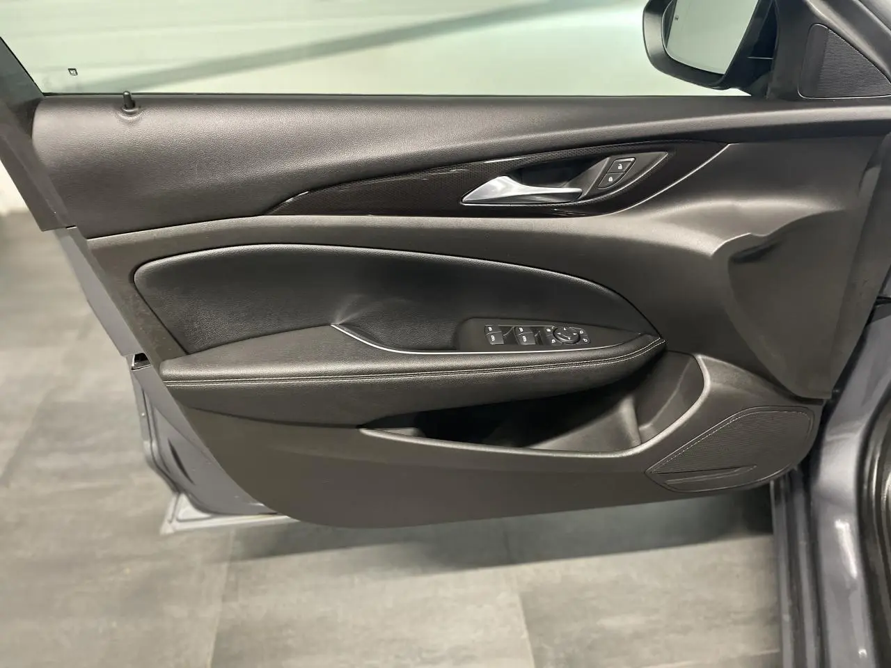 Panneau de porte côté gauche noir avec commandes électriques sur Opel Insignia Grand Sport gris clair, vue intérieure.