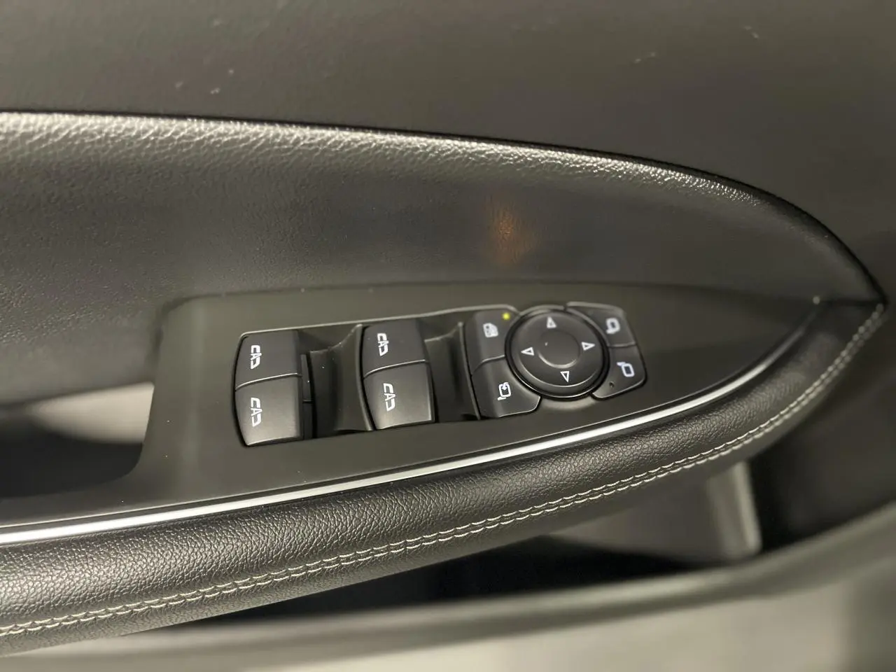 Gros plan sur la commande des vitres et rétroviseurs côté conducteur en cuir noir avec surpiqûres blanches dans une Opel Insignia Grand Sport 2021.