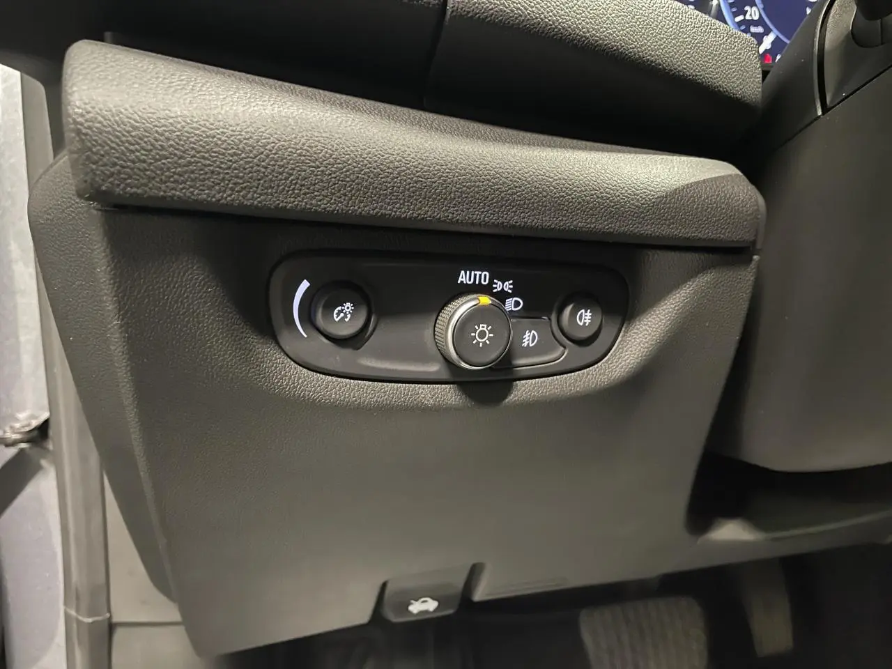 Gros plan sur les commandes d'éclairage noires sous le tableau de bord d'une Opel Insignia Grand Sport gris clair.
