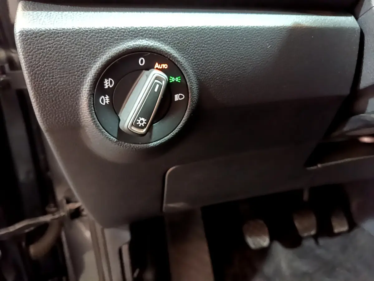 Gros plan sur le bouton de commande des phares à gauche du volant dans l'habitacle du Volkswagen T-Roc gris foncé 2021.