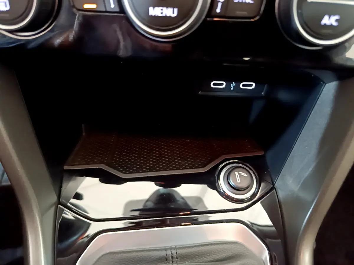 Gros plan sur la console centrale noire du Volkswagen T-Roc 2021, avec prise USB et allume-cigare visible.