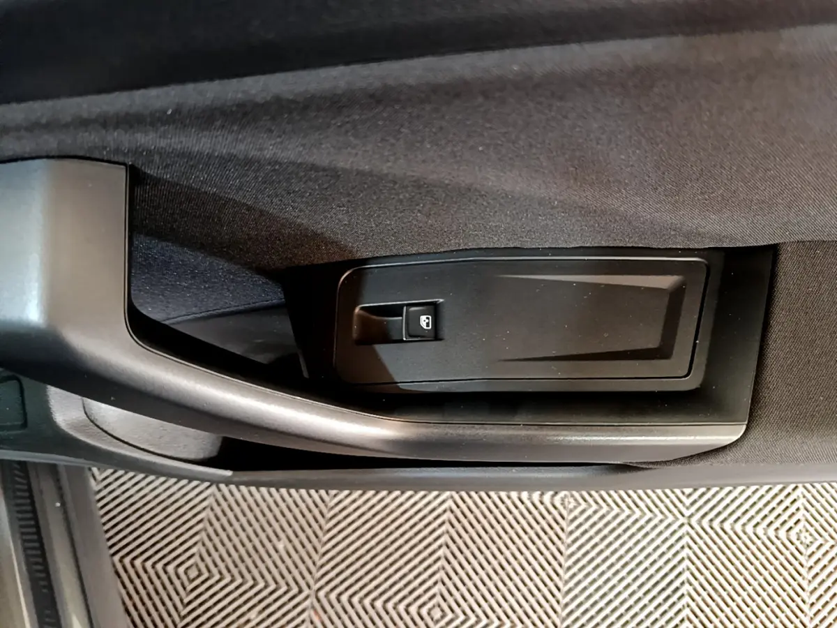 Poignée de porte intérieure côté conducteur du Volkswagen T-Roc gris foncé, avec bouton de verrouillage intégré.