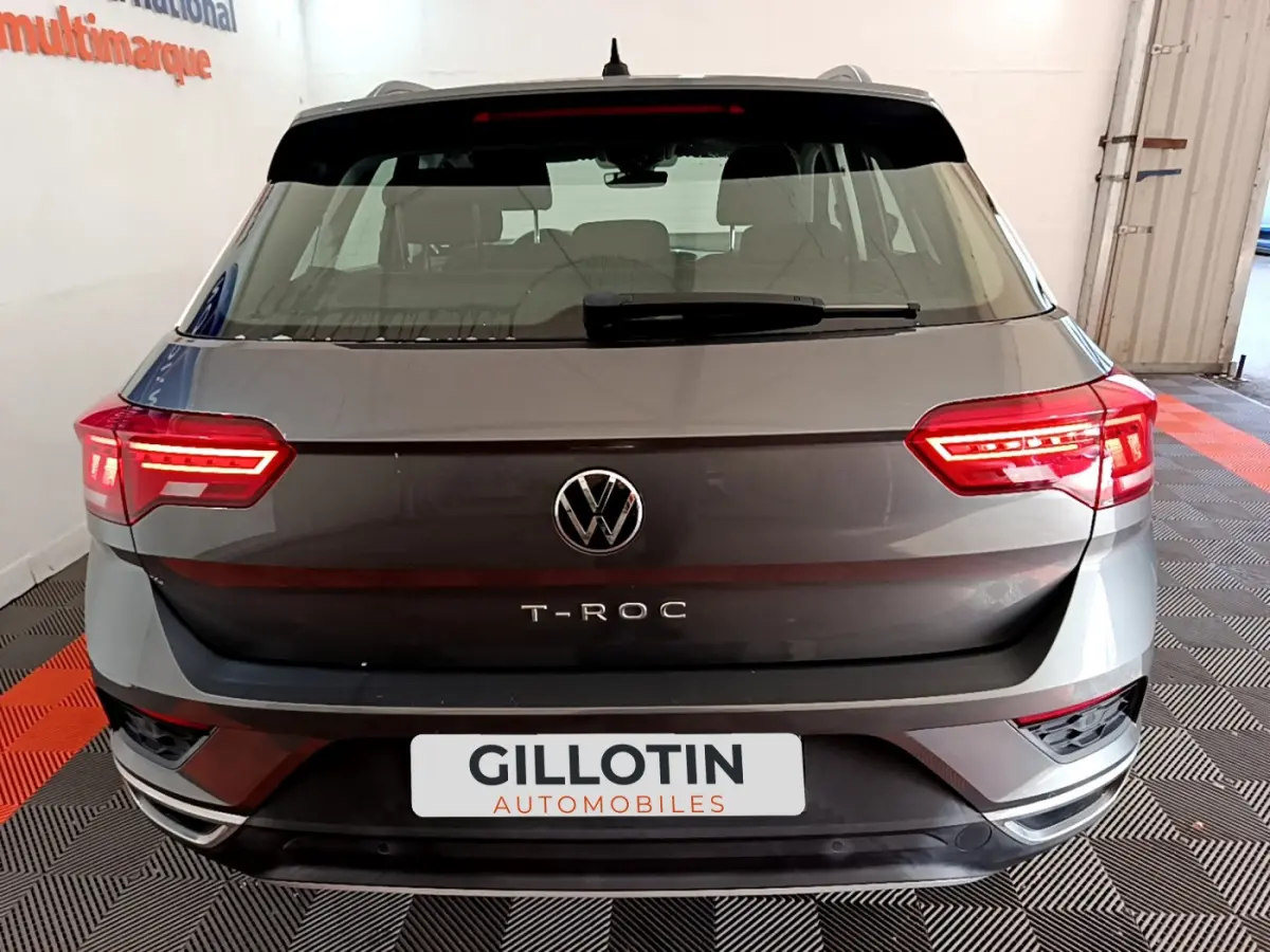 Vue arrière d'un Volkswagen T-Roc gris foncé avec feux LED allumés dans un showroom.