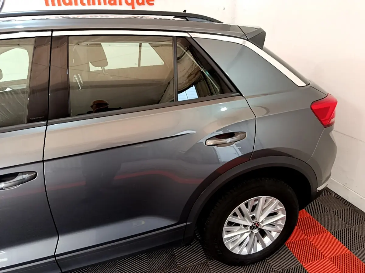 Vue côté droit arrière du Volkswagen T-Roc gris foncé 2021 avec jantes alliage et barres de toit noires.