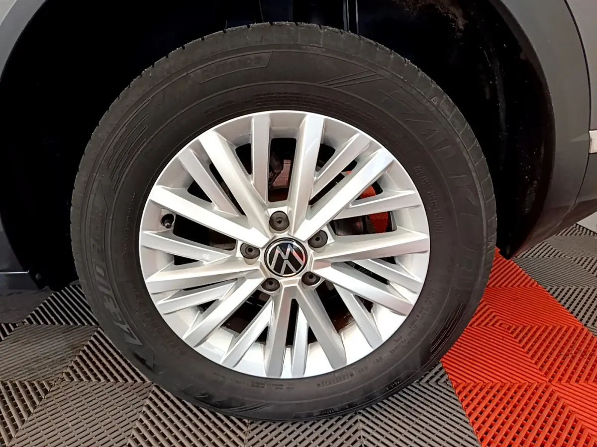 Gros plan sur la roue avant droite avec jante argentée du Volkswagen T-Roc gris foncé 2021.