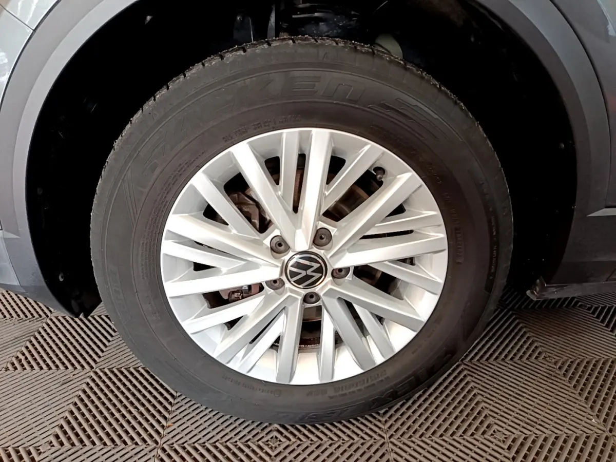 Gros plan sur la roue avant droite avec jante argentée et logo Volkswagen du T-Roc gris foncé 2021