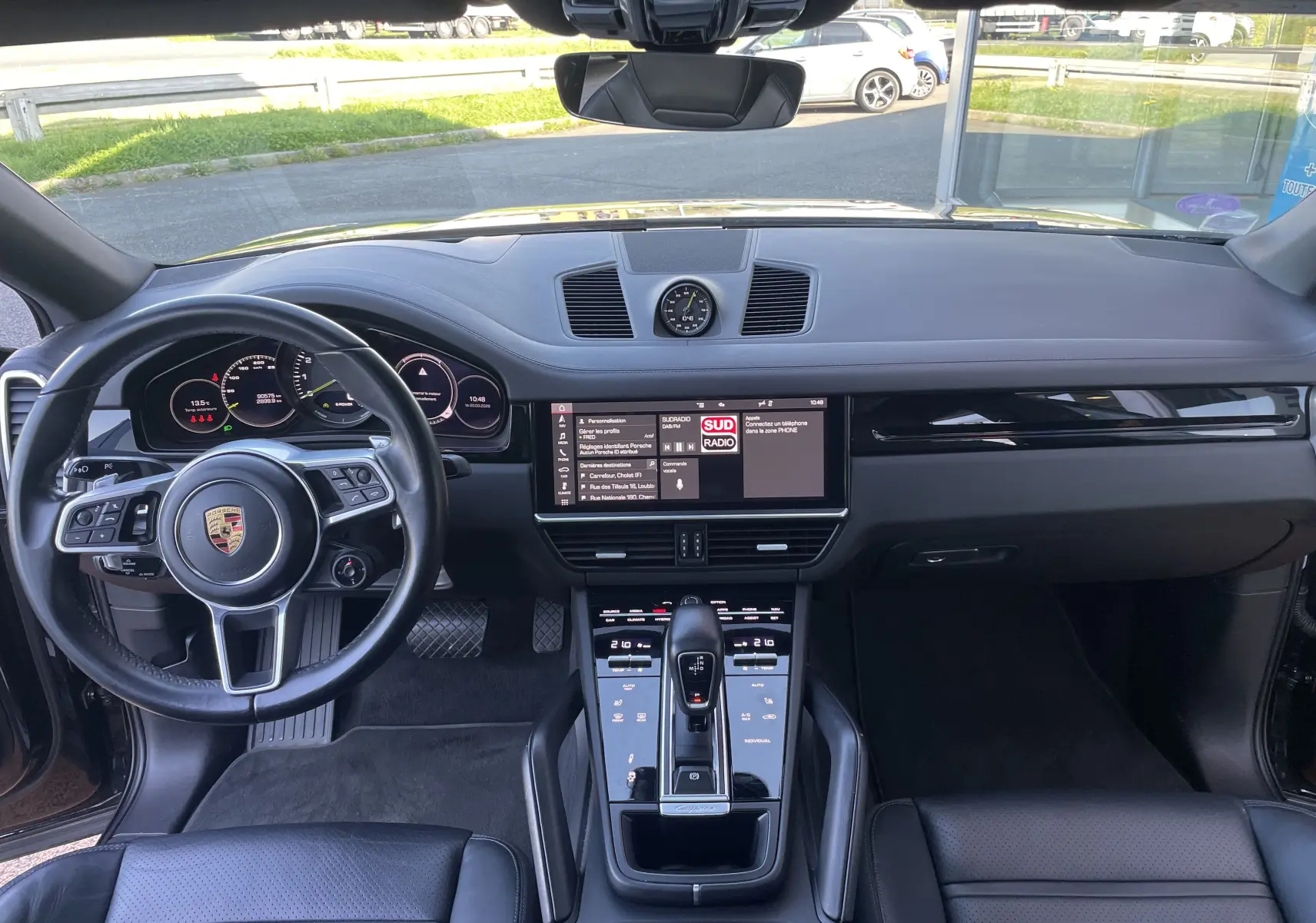 Vue intérieure avant du Porsche Cayenne Coupé e-Hybrid 2021 avec tableau de bord noir et écran tactile central allumé.