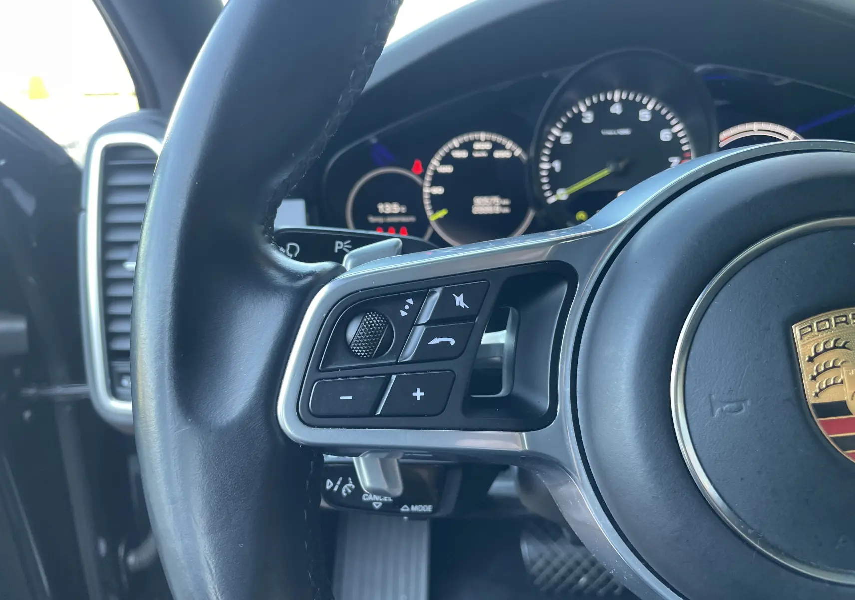Gros plan sur le volant cuir multifonction noir de la Porsche Cayenne Coupé E-Hybrid 2021 avec commandes au volant.