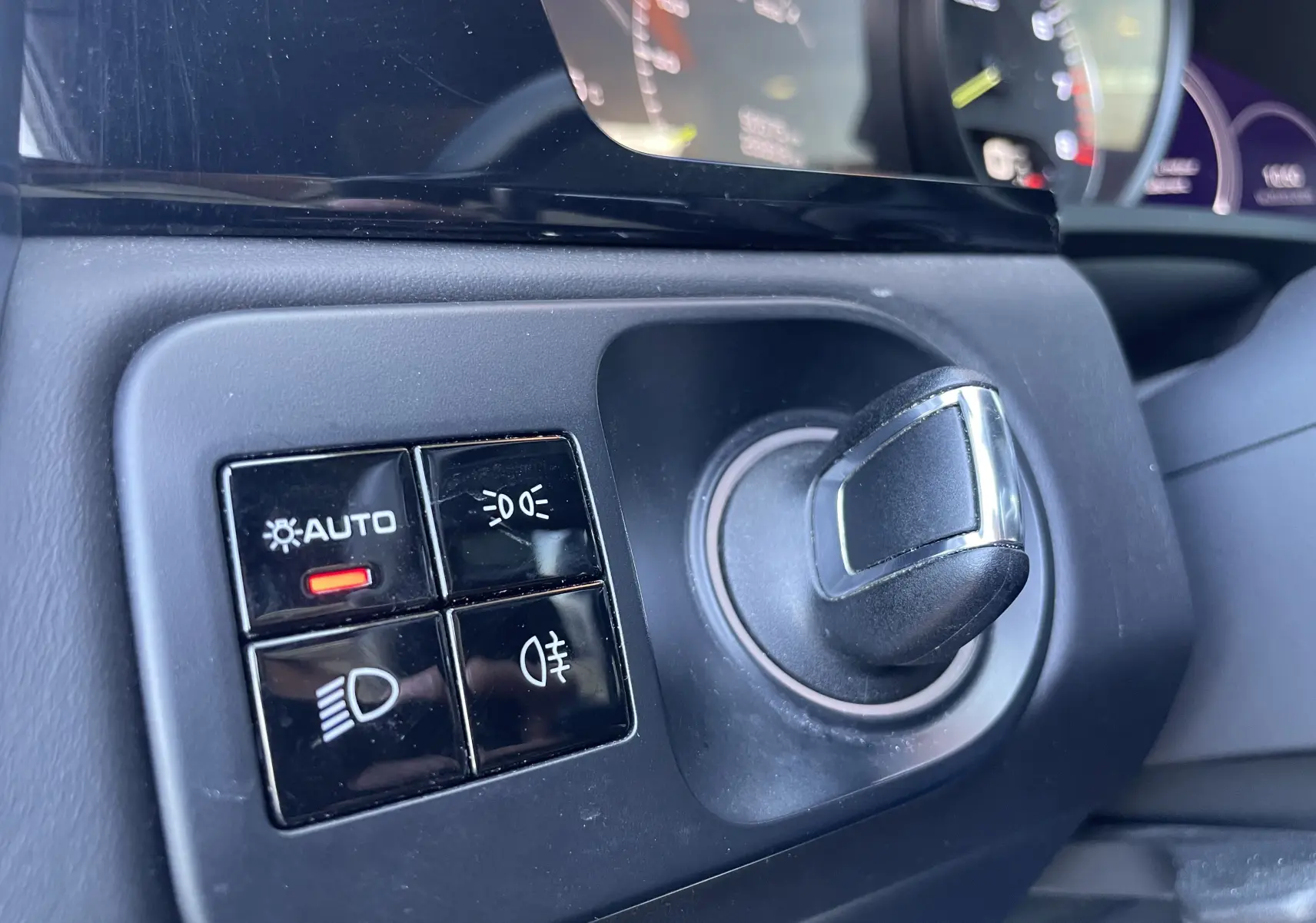 Gros plan sur le sélecteur de phares noir et chrome du tableau de bord intérieur d’un Porsche Cayenne Coupé e-Hybrid 2021.