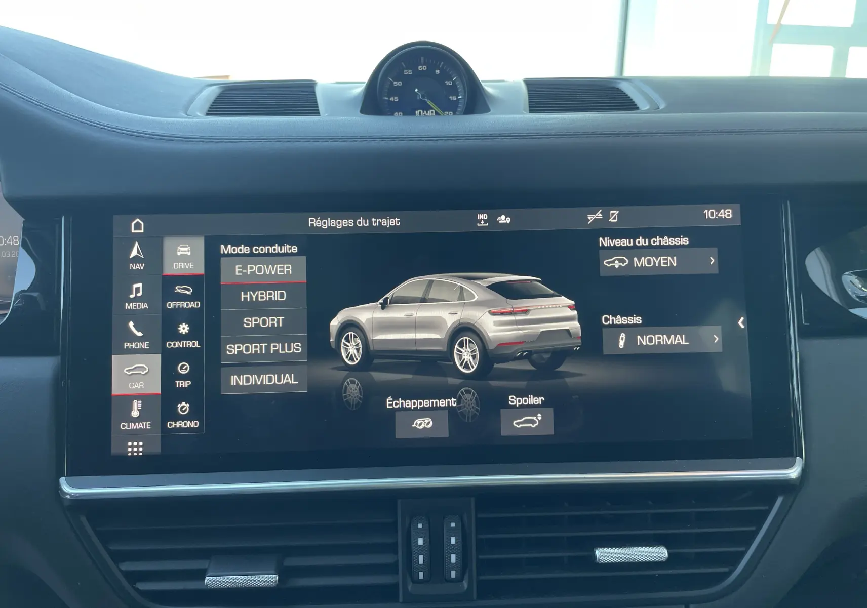 Écran central affichant les réglages de conduite avec une image 3/4 arrière d'un Porsche Cayenne Coupé gris.