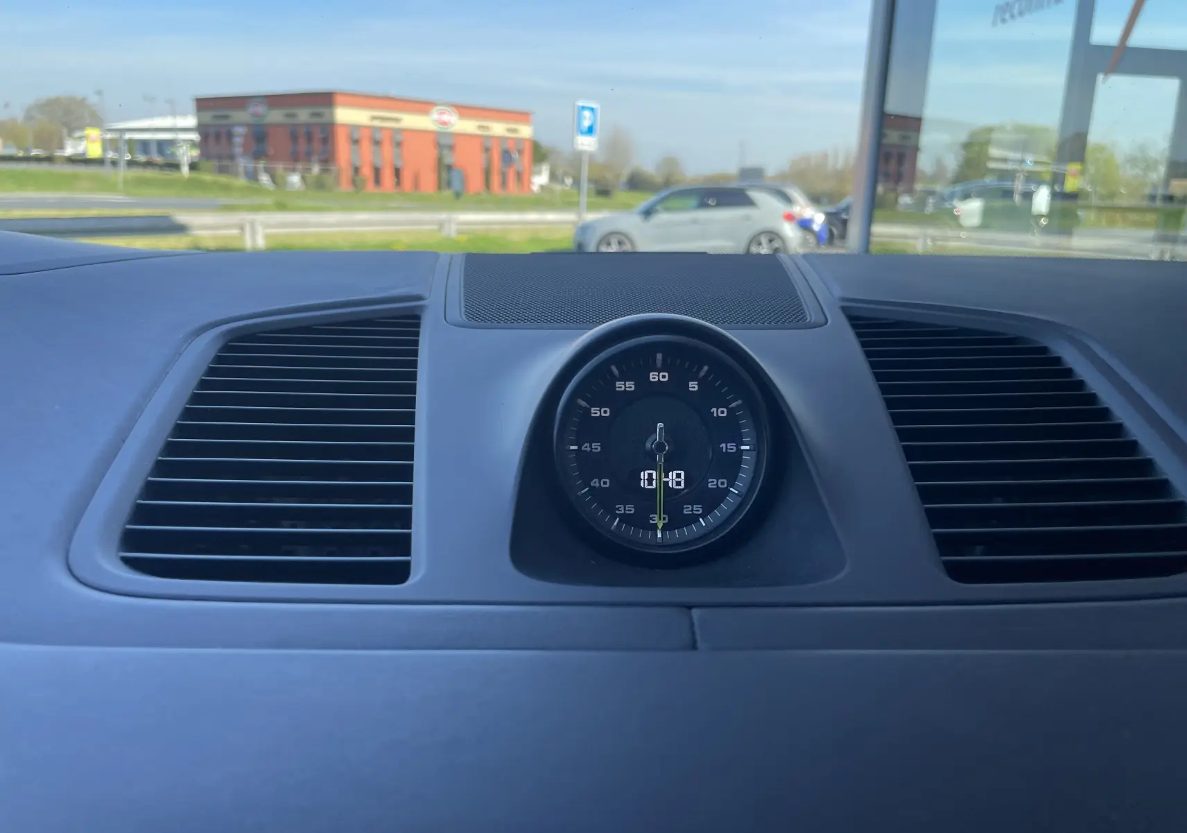 Vue intérieure centrée sur l'horloge analogique du tableau de bord du Porsche Cayenne Coupé hybride noir 2021.