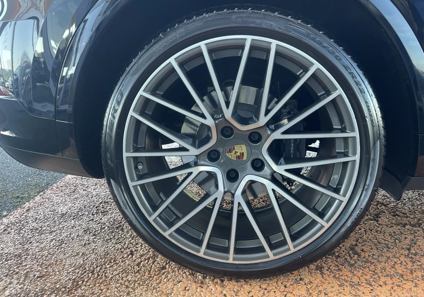 Gros plan sur la jante alu 22 pouces grise du côté arrière droit du Porsche Cayenne Coupé E-Hybrid noir.