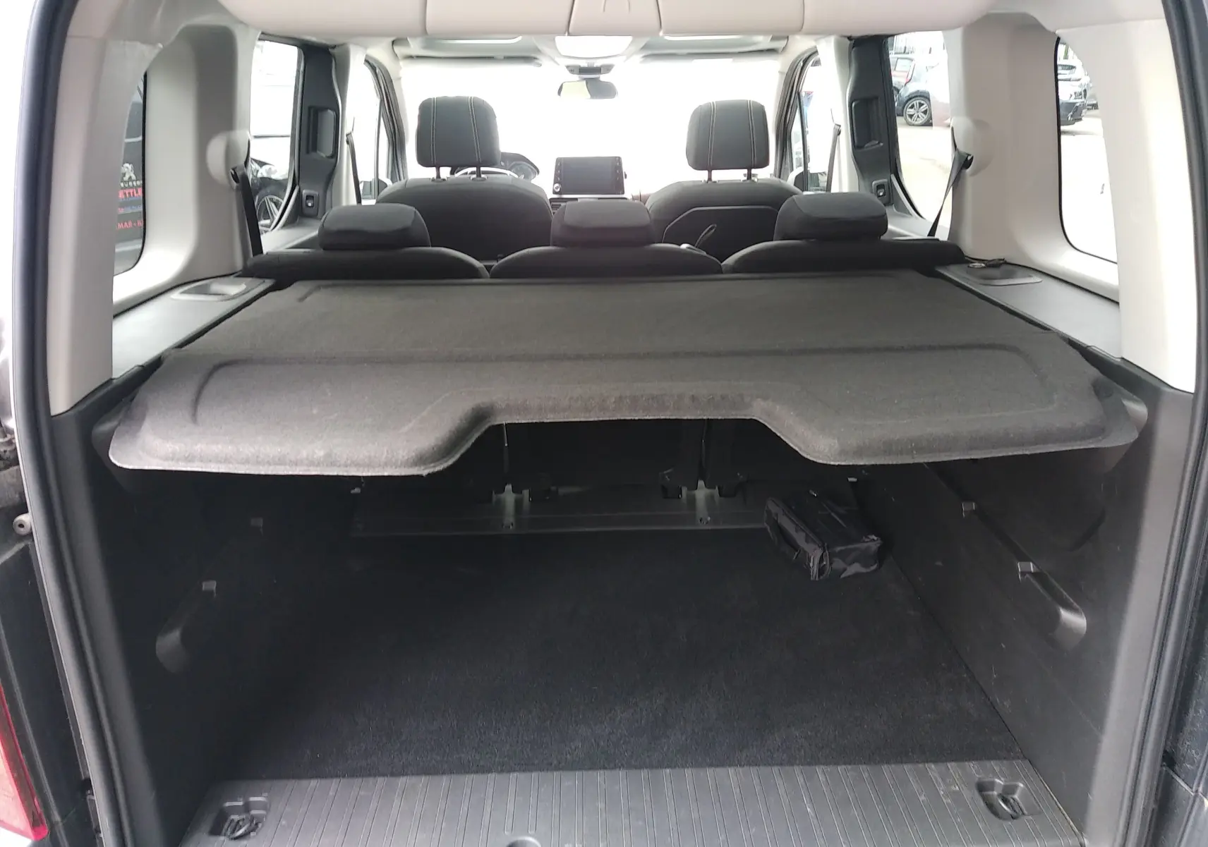 Vue arrière du coffre du Peugeot Rifter gris platinium 2022, avec cache-bagages et sièges arrière visibles.