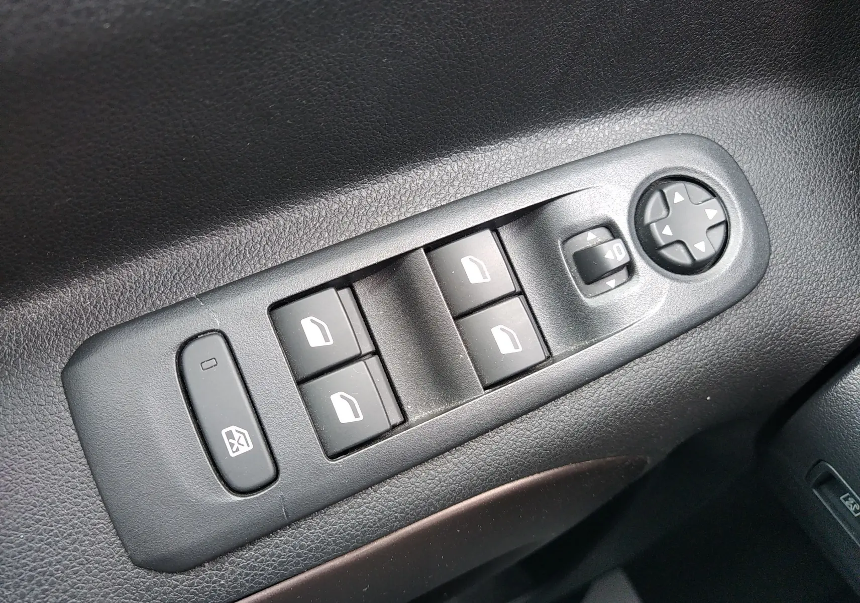 Gros plan sur les commandes de lève-vitres et réglage des rétroviseurs côté conducteur du Peugeot Rifter gris platinium 2022.