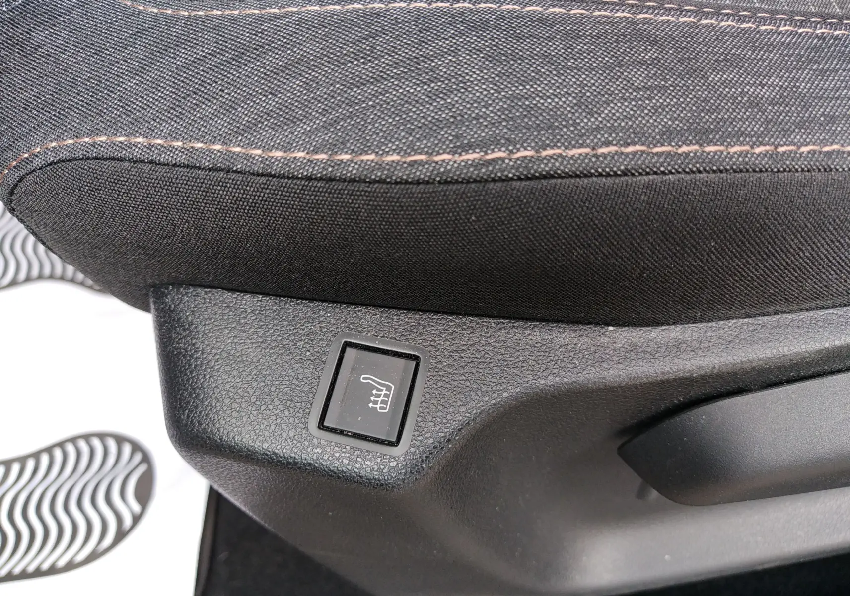 Gros plan sur le bouton de siège chauffant sur la base d’un siège en tissu noir du Peugeot Rifter gris platinium 2022.