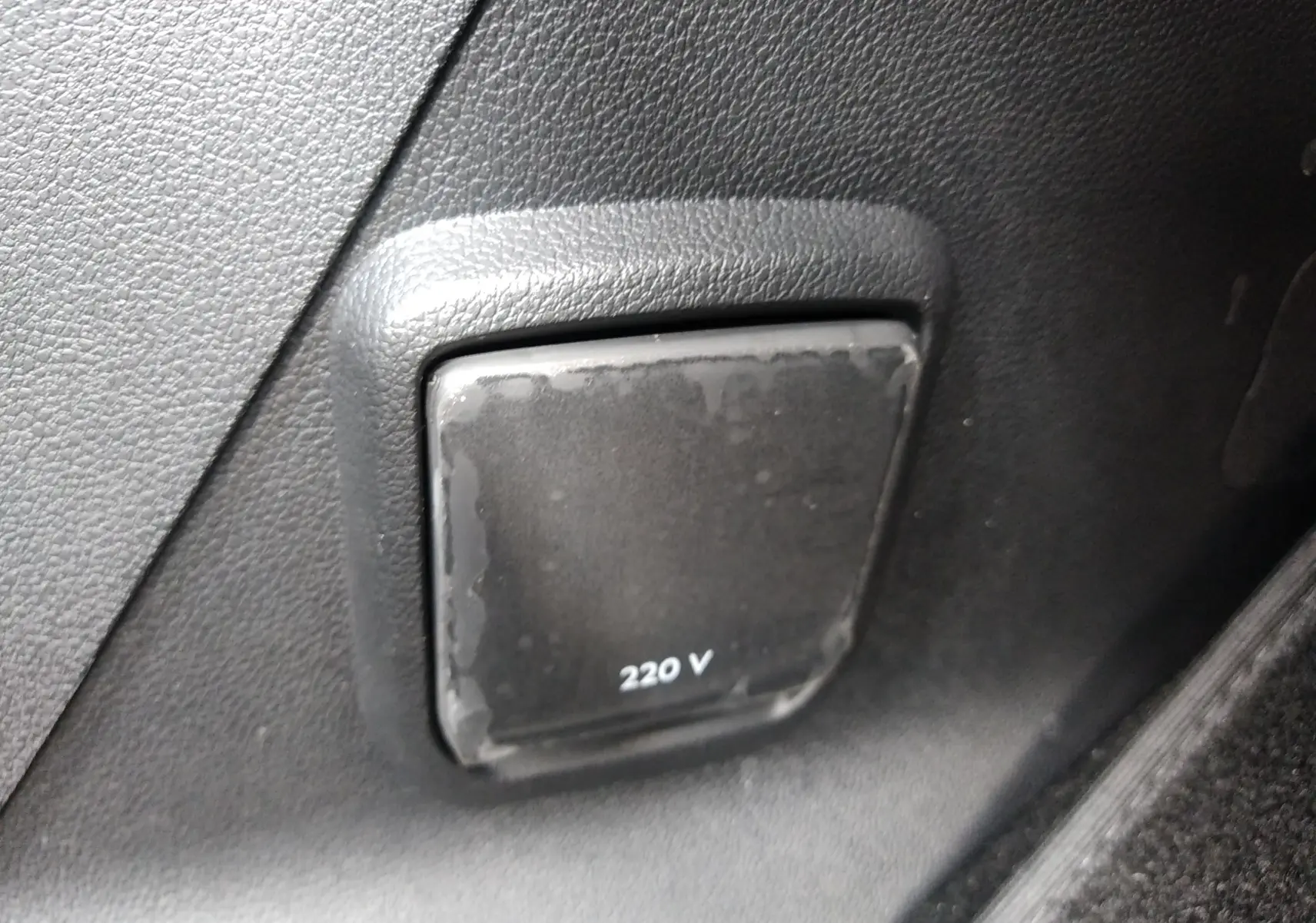 Prise 220 V noire intégrée dans le panneau intérieur gris foncé du Peugeot Rifter 1.5 BlueHDI 130ch GT 2022.