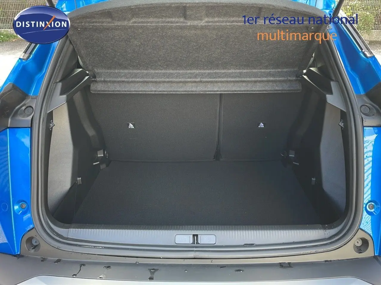 Coffre ouvert d'un Peugeot 2008 bleu Vertigo Metal, montrant l'espace de chargement vide et la trappe arrière.