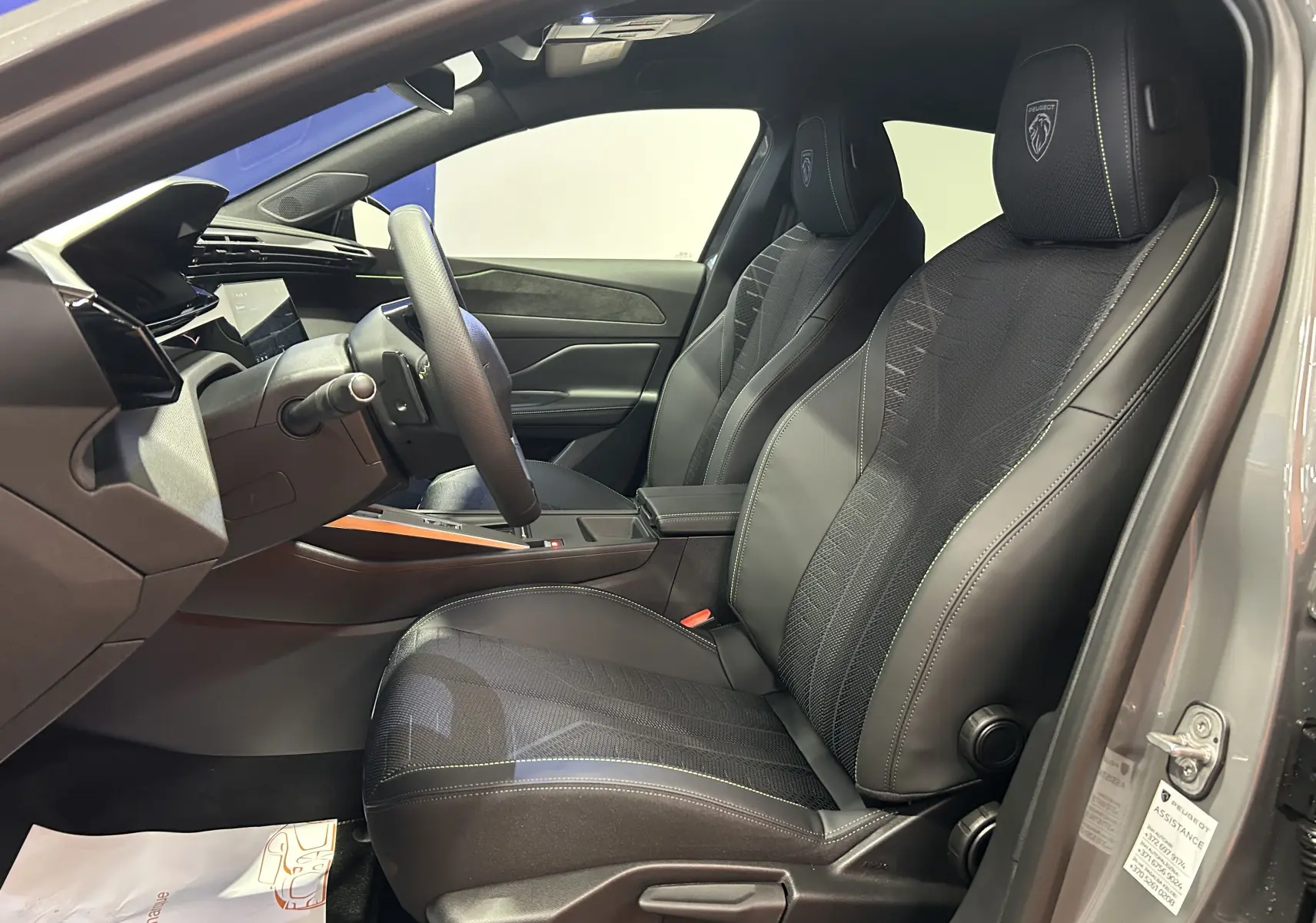 Vue intérieure côté conducteur de la Peugeot 308 III Ph.2 Hybrid 145 GT avec sièges cuir et tissu gris Selenium.