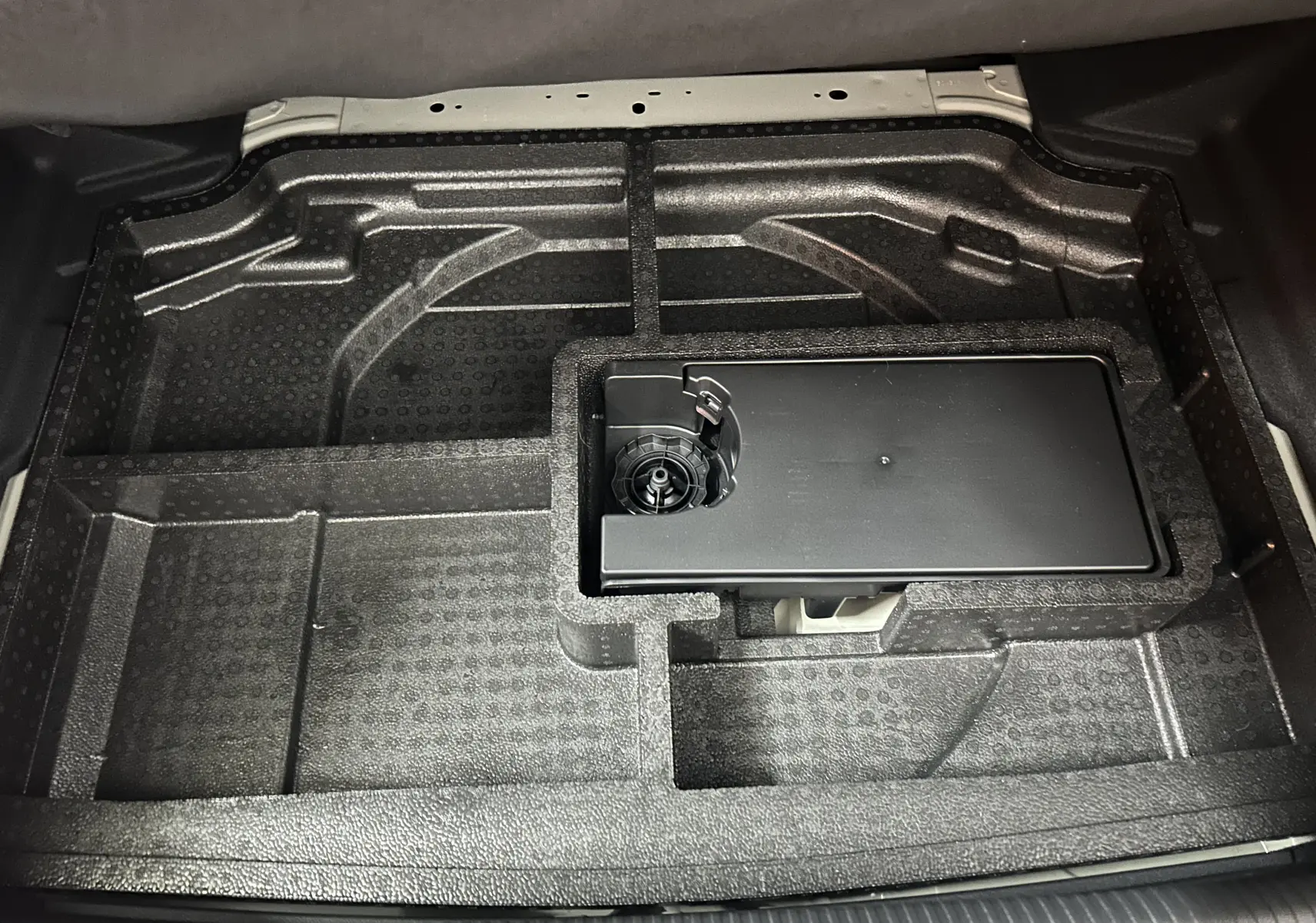 Vue plongeante sur le compartiment de rangement sous le coffre de la Peugeot 308 gris Selenium, avec emplacement pour kit de réparation.