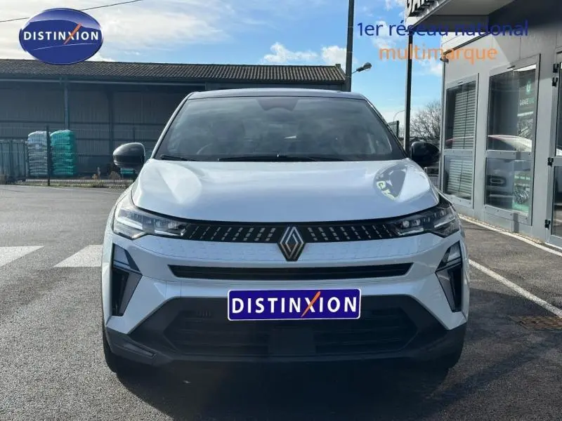 Vue avant d'un Renault Captur 2025 blanc nacré avec toit noir, calandre noire et logo Renault central visible.