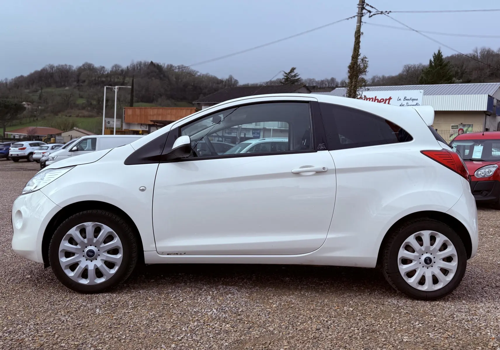 Profil latéral droit d'une Ford KA blanche à 3 portes, avec jantes alliage et vitres teintées.