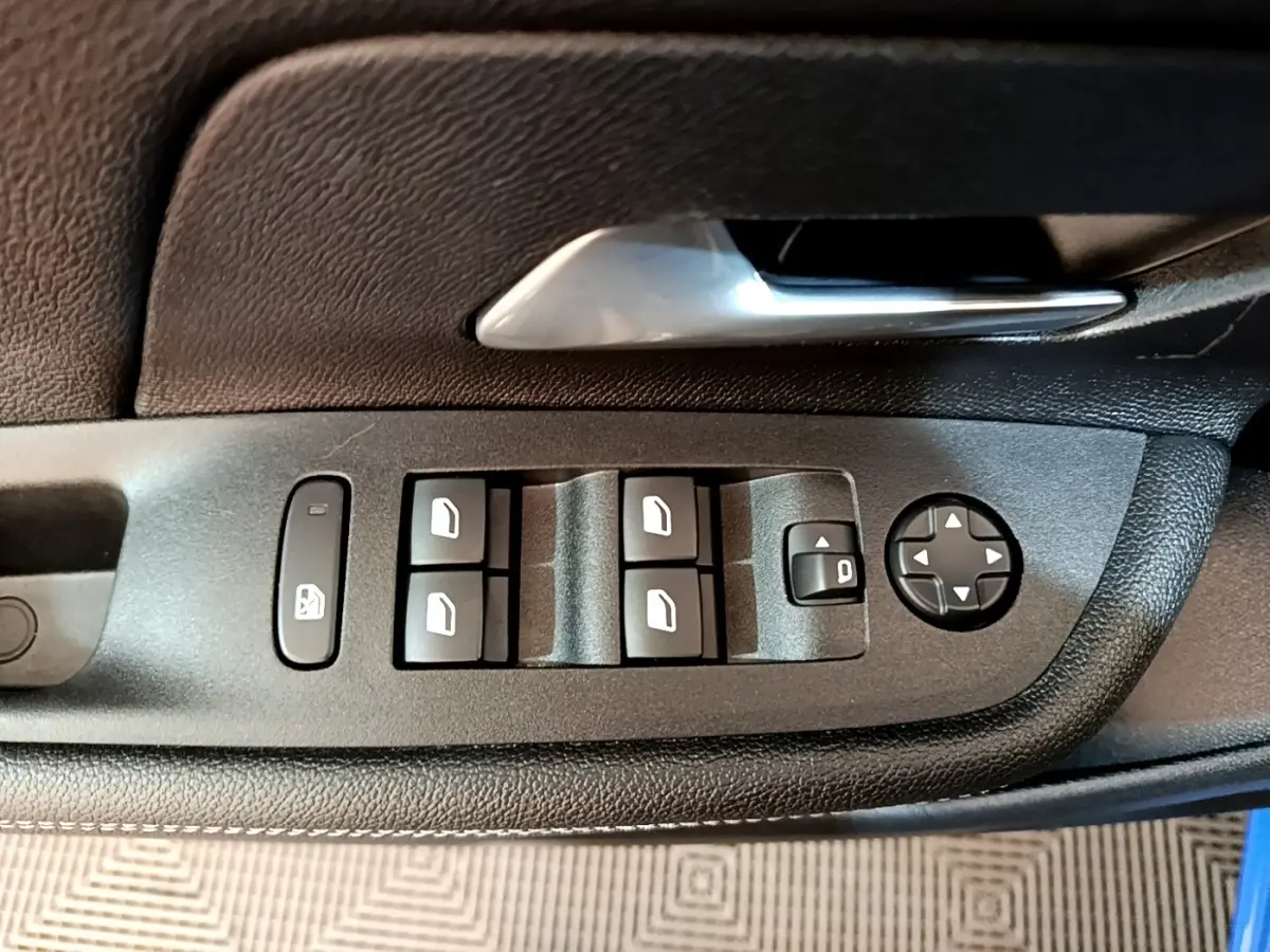 Gros plan sur les commandes des vitres et rétroviseurs côté conducteur de l’Opel Mokka bleu 2024.